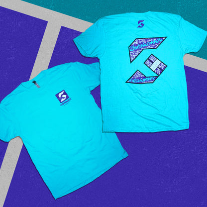 Two turquoise t-shirts with a logo on a blue and gray checkered background